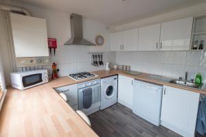 a kitchen with white cabinets and a washing machine at 34 Surfview Beach House in Newquay