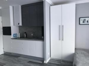 una cocina blanca con armarios blancos y fregadero en Apartament Villa Marea en Międzyzdroje