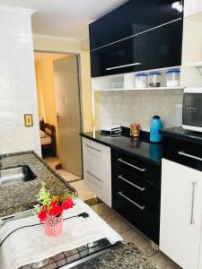 eine Küche mit schwarzen und weißen Schränken und einem Tisch mit Blumen in der Unterkunft Apartamento Mobiliado em Limeira in Limeira
