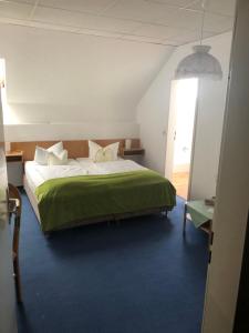 ein Schlafzimmer mit einem großen Bett und einer grünen Decke in der Unterkunft Hotel-Pension Am Mühlberg in Lübbenau