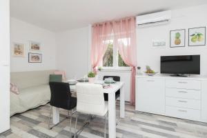 ein Wohnzimmer mit einem Tisch mit Stühlen und einem TV in der Unterkunft Apartman Roko in Petrcane