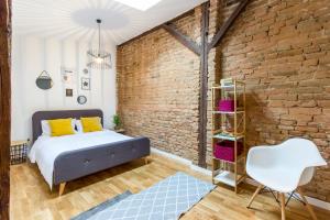 1 dormitorio con pared de ladrillo, cama y silla en Quiet Old Town Hideout, en Cluj-Napoca