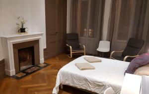 - une chambre avec un lit, deux chaises et une cheminée dans l'établissement L'Haussmannien Stéphanois, à Saint-Étienne