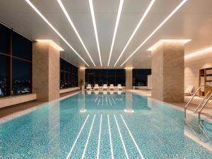 a large swimming pool in a hotel lobby with lights at Novotel Ambassador Seoul Yongsan in Seoul