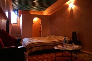 a bedroom with a bed and a table with a bottle on it at Riad Felloussia in Meknès