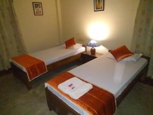 two twin beds in a room with a lamp at Happy Homes in Guwahati