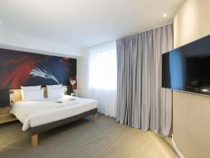 a hotel room with a bed and a flat screen tv at Novotel Poitiers Site du Futuroscope in Chasseneuil-du-Poitou