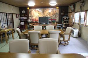 una sala da pranzo con tavoli, sedie e TV di Towadako Backpackers a Towada