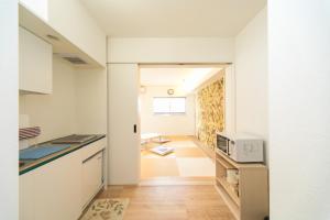 eine Küche mit weißen Schränken und einer Mikrowelle in der Unterkunft Kevin's Place II (Annex) in Kyoto