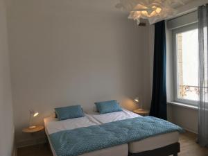 a bedroom with a bed with blue sheets and a window at LA VILLE A LA MER N°1 in Concarneau