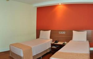 um quarto com duas camas e uma parede vermelha em Hotel Vollare em Osasco