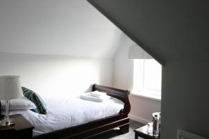 um quarto com uma cama com lençóis brancos e uma janela em Ferndale Lodge em Torquay