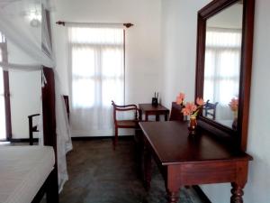 a bedroom with a table and a mirror and a bed at Thanu Beach Villa in Ambalangoda