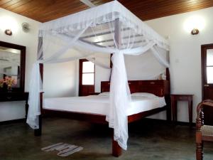 Un dormitorio con una cama con dosel y cortinas blancas. en Thanu Beach Villa, en Ambalangoda 22 fotos más