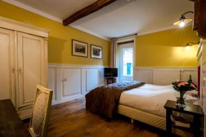 een slaapkamer met gele muren en een bed met een tafel bij Auberge de Smockelaer in Heijenrath