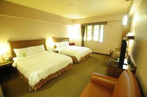 um quarto de hotel com duas camas e um sofá em Kindness Hotel Taitung Branch em Taitung City