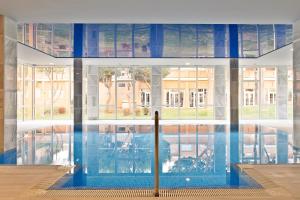 a swimming pool in a building with a large window at Hipotels Playa La Barrosa - Adults Only in Chiclana de la Frontera