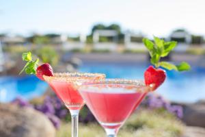 two cocktails with strawberries in them sitting on a table at Hipotels Playa La Barrosa - Adults Only in Chiclana de la Frontera