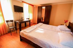 a bedroom with a bed and a table and a desk at Green Garden Guest House in Tskaltubo
