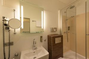 a bathroom with a sink and a shower and a mirror at Heikotel - Stadtpark Residenz in Hamburg