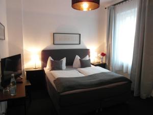 Dormitorio con cama, escritorio y TV en Hotel Frankfurter Hof, en Limburg an der Lahn