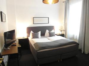 a bedroom with a bed and a desk and a television at Hotel Frankfurter Hof in Limburg an der Lahn
