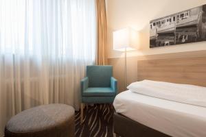 a hotel room with a bed and a blue chair at Heikotel - Stadtpark Residenz in Hamburg