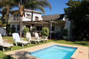 a backyard with a swimming pool and chairs and a house at Randrivier in Robertson