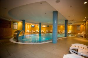 una grande piscina in un hotel con sedie e tavoli di Hotel Colosseo & Spa a Shkodër