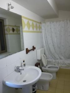 ein Badezimmer mit einem Waschbecken, einem WC und einem Spiegel in der Unterkunft on the beach in Gioiosa Marea