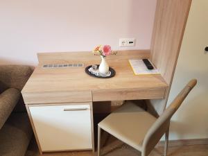 a small desk with a vase of flowers on it at Guest House Vila Moj Mir in Rateče