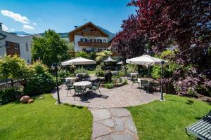 un patio con mesas, sillas y sombrillas en Hotel Zum Mohren, en Tesimo