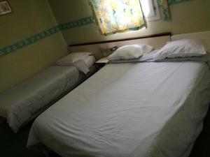 two beds in a room with a large white bed at Hôtel l'Eden in Brix