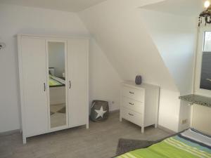 - une chambre avec un lit, une commode et un miroir dans l'établissement VIDS10C15-FeHaus-Huus-Oostsied, à Vitzdorf