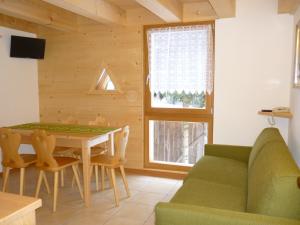 ein Wohnzimmer mit einer grünen Couch und einem Tisch in der Unterkunft Maso Fior di Bosco - Val di Rabbi - Esercizio Rurale in Rabbi