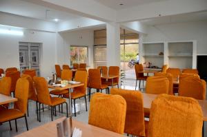 un comedor con sillas naranjas, mesas y mesa en Chitrakoot Garden and Resorts, en Pushkar