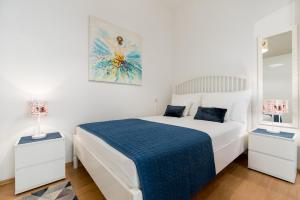 a white bedroom with a bed with a blue blanket at Apartment Kala in Split