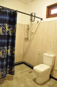łazienka z prysznicem, toaletą i zasłoną prysznicową w obiekcie sigiriya flower guest w mieście Sigirija