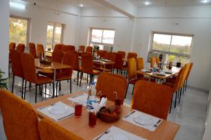 un comedor con mesas, sillas y ventanas en Chitrakoot Garden and Resorts, en Pushkar