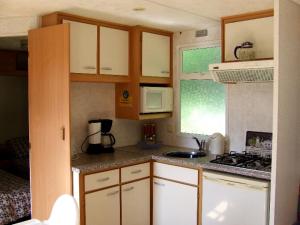 a small kitchen with white cabinets and a stove at Stacaravan 6 persoons - Camping Le Soustran in Neuvic