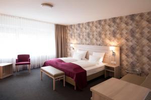 ein Hotelzimmer mit einem Bett und einem Stuhl in der Unterkunft Hotel Senator München in München