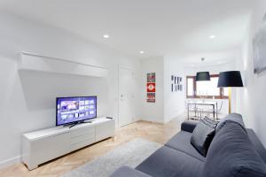 a living room with a blue couch and a tv at Villanueva Apartments by Flatsweethome in Madrid