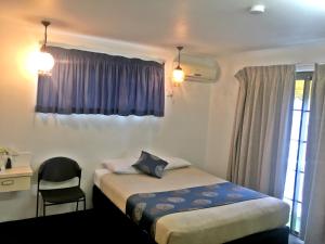 - une chambre avec un lit, une chaise et une fenêtre dans l'établissement Siesta Villa Motel, à Gladstone