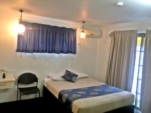 a bedroom with a bed and a chair and a window at Siesta Villa Motel in Gladstone