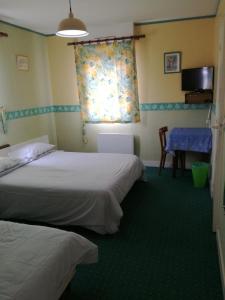 a room with two beds and a table and a window at Hôtel l'Eden in Brix