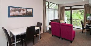 a dining room with a table and red chairs at Breakwater Motel in Paihia