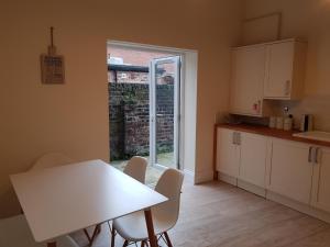 a kitchen with a white table and chairs and a window at Tunstall Serviced Home in Sunderland