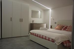 a white bedroom with a bed and a cabinet at Anthos Casa Vacanze in SantʼOmero