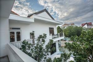 a white house with trees in front of it at Oleander Garden Homestay in Hoi An