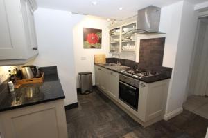a kitchen with white cabinets and a stove top oven at Binswood Garden Apartment in Leamington Spa